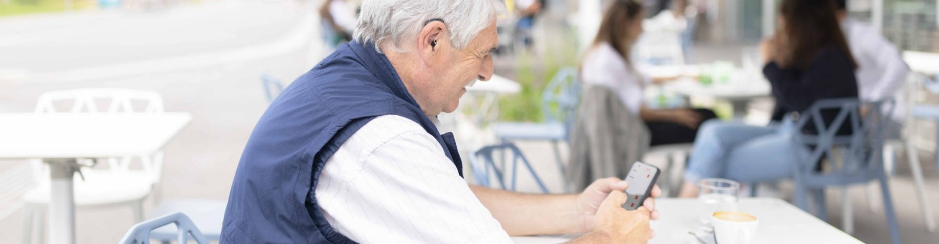 AudioKey 3 - We Value Your Feedback An elderly bimodal SONNET 3 and hearing aid user adjusting SONNET 3 settings with ease using the AudioKey 3 app
